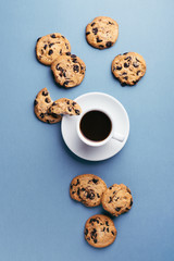 Wall Mural - American cookies with chocolate chips and a cup of coffee on blue background. Top view.