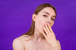 © yurakrasil - sleepy young teen girl yawns on purple background in studio