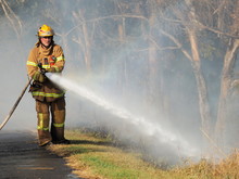 Melbourne, Australia - April 13, 2018: Fire Fighter With A Hose At A Bush Fire In An Suburban Area Of Knox City In Melbourne East.