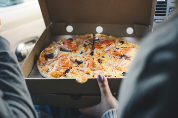 Friends eating pizza in the car.