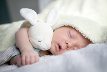 Newborn Baby Boy Portrait On White Carpet Closeup. Motherhood And New Life Concept