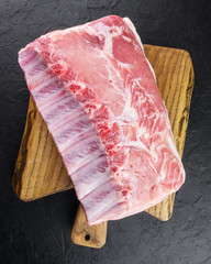 Wall Mural - Fresh raw pork piece on wooden board on black background. Food photography