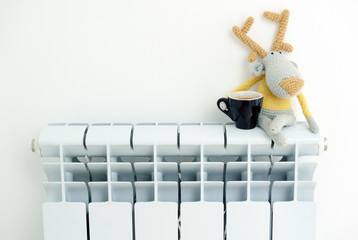 Wall Mural - Knitted deer sits on the radiator with a cup in his hand