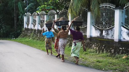 women head-carrying and walking down the street