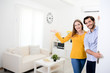 © W PRODUCTION - cheerful young couple man and woman welcome friends at open front door new student home apartment