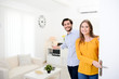 © W PRODUCTION - cheerful young couple man and woman welcome friends at open front door new student home apartment