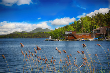 Wooden dock with yachts on the blue lake and behind him is stone castle on the hill and blue sky.