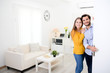 © W PRODUCTION - cheerful young couple man and woman welcome friends at open front door new student home apartment