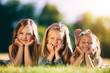 © Photocreo Bednarek - Three smiling little girls laying on the grass in the park.