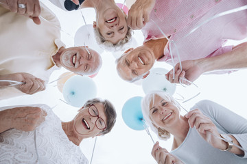 Wall Mural - Low angle of happy senior people in the circle with balloons during party