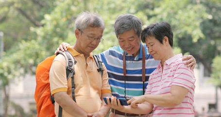 Wall Mural - Senior old friends go travel together with backpack, cellphone and camera