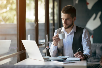 Young businessman working on a plan of Internet project on the laptop. Man discusses business matters by phone. Working computer for internet research. Digital marketing. Development