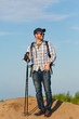 © snedorez - Photo of tourist man in sunglasses with sticks for walking on hill