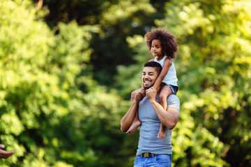 Wall Mural - Portrait of young father carrying his daughter on his back