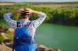 © snedorez - Picture from back of young tourist with backpack with hands behind head against background of mountain landscape, lake