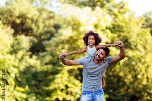 Fotomural Portrait of young father carrying his daughter on his back