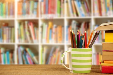 Poster - Composite image of stack of books by mug with colored pencils on