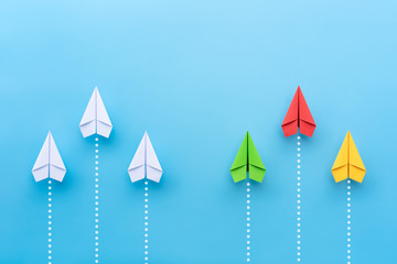 Wall Mural - Group of white paper plane and with group colorful paper plane on blue background. Business competition, different vision creative and innovative solution concept.