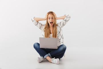 Poster - Portrait of surprised young casual girl looking at laptop