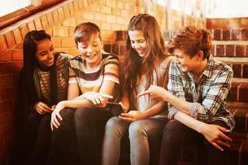 Poster - Smiling school students sitting on the staircase using mobile