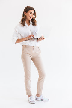 portrait of adorable smiling woman with long brown hair holding and looking at silver laptop, isolat