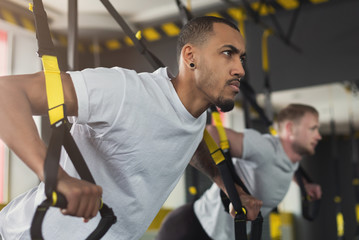 Wall Mural - Men performing TRX training in gym