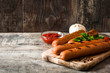 Grilled sausages and ketchup on wooden table. Copyspace

