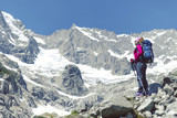Fototapeta Las - Trek around Mont Blanc. The girl is walking along the trail with a backpack.
