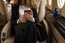 Businesswoman Using Mobile Phone In Private Jet