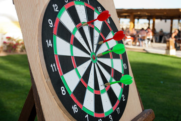 Darts with arrows. Playing darts during summer day. Arrows reached the target. Game over.