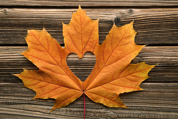 dry maple leaf with heart on brown wooden table