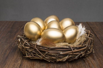 Wall Mural - Nest with golden eggs on a wooden background. The concept of successful retirement