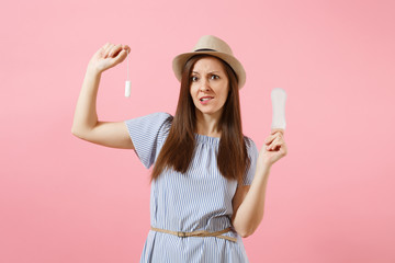 Portrait of young woman in blue dress holding sanitary napkin, tampon for variant safety menstruation days isolated on pink background. Medical healthcare, gynecological, choice concept. Copy space.