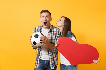 Wall Mural - Young happy cheerful couple supporter, woman man, football fans cheer up support team, holding red heart love, soccer ball isolated on yellow background. Sport family leisure people lifestyle concept