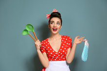 Funny Young Housewife With Oven Mitten And Cooking Utensils On Color Background