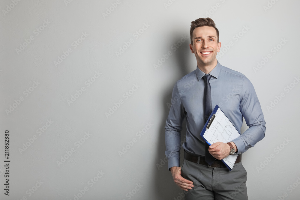 Male real estate agent with clipboard on grey background - obrazy, fototapety, plakaty 