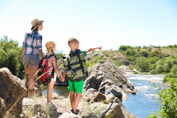 Wall Mural - young woman with children on rock near river. summer camp