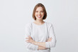 Portrait of cheerful attractive young woman in longsleeve standing with arms crossed and smiling isolated over white background Looks confident