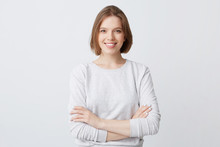 Smiling Beautiful Young Woman In Longsleeve Standing With Arms Crossed And Feeling Confident Isolated Over White Background Looks Successful