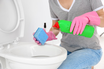 Woman cleaning toilet bowl in bathroom