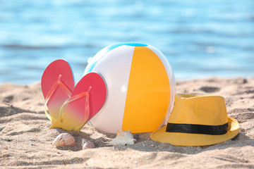 Poster - Inflatable ball, hat and flip flops on sand near sea. Beach object