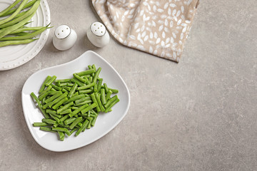 Plates with fresh green beans on table, top view