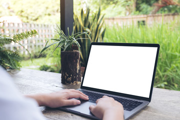 Mockup image of a woman using and typing on laptop with blank white desktop screen with nature background