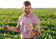 © Zoran Zeremski - Young farmer standing in filed holding tablet in his hands and examining soybean corp.