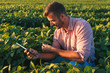 © Zoran Zeremski - Young farmer in filed holding tablet in his hands and examining soybean corp.