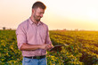 © Zoran Zeremski - Young farmer standing in filed holding tablet in his hands and examining soybean corp at sunset.