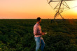 © Zoran Zeremski - Young farmer holding tablet in his hands and adjusts irrigation system on soybean field at sunset.