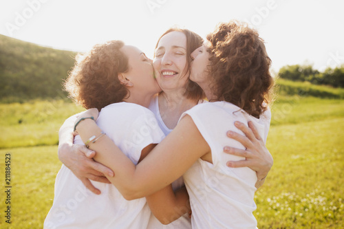 Happy beautiful mother woman hugging her beautiful curly daughters in white T-sh Tableau sur Toile
