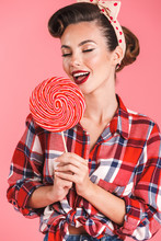 Pin-up Woman Isolated Over Pink Background Holding Candy Lollipop.