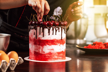 girl chef confectioner making an oil cake with a cherry. concept production process at home cakes to order customers. smears cream cake spatula. background image.